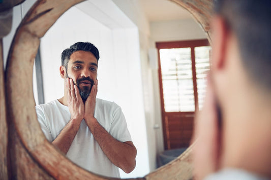 man using beard oil in mirror
